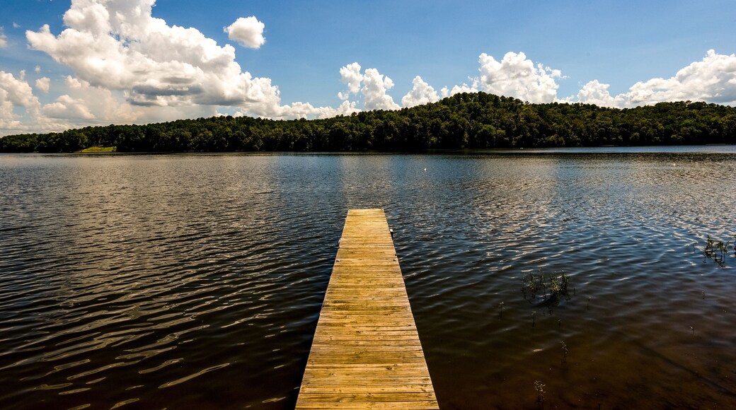 Small dock jutting into calm lake with hills and clouds in distance