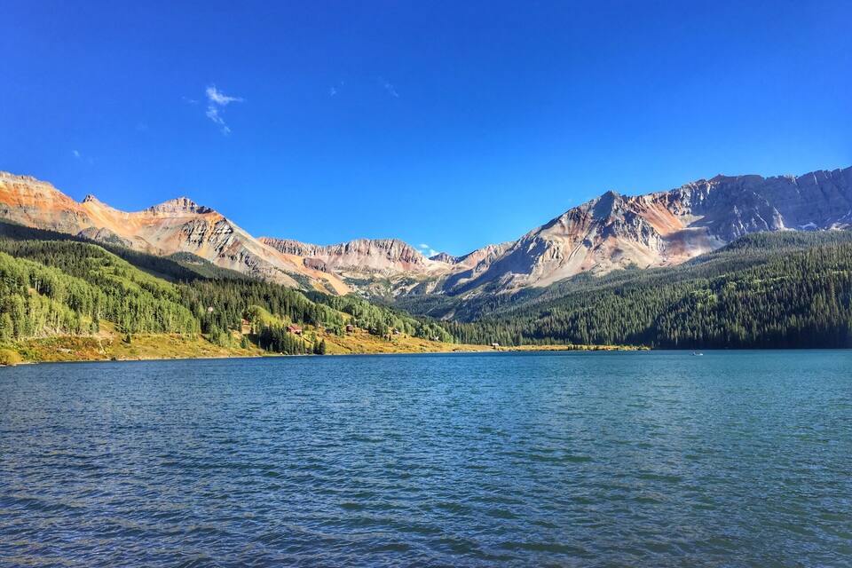 Ein See, umgeben von Bergen, mit blauem Himmel.