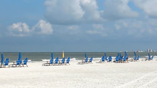 Panoramic view of beach chairs on the white sands of Fort Myers Beach facing the Gulf of Mexico.