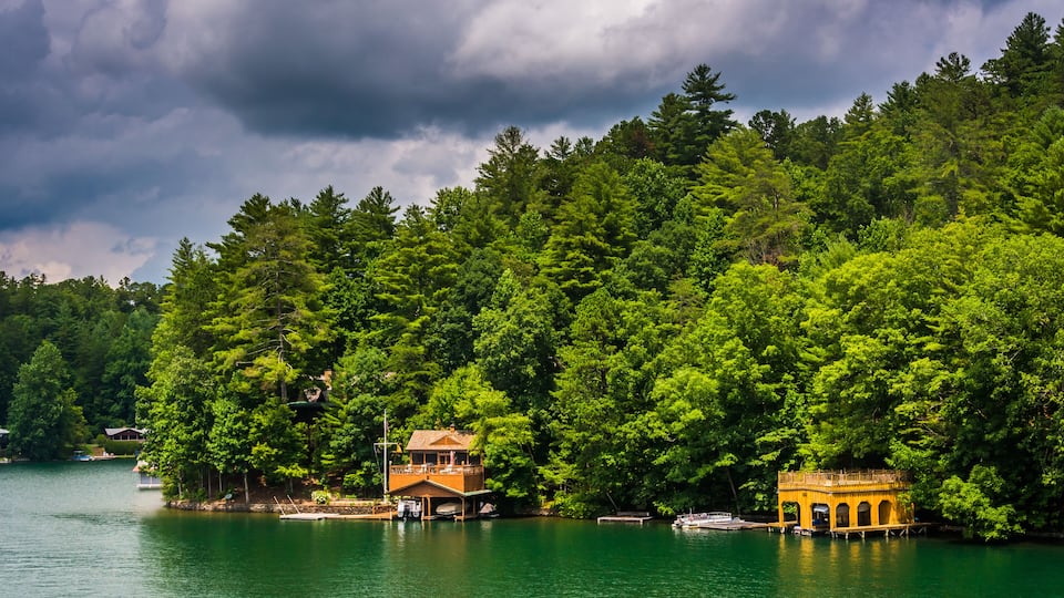 A lake surrounded by dense forest, with two wooden structures on stilts.