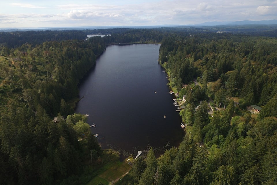 A large lake surrounded by dense forest and mountains in the background.