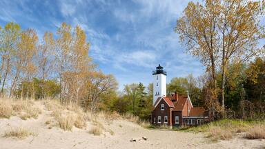 A lighthouse, a brick house, and autumn trees.