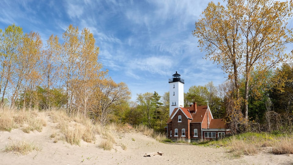 A lighthouse, a brick house, and autumn trees.