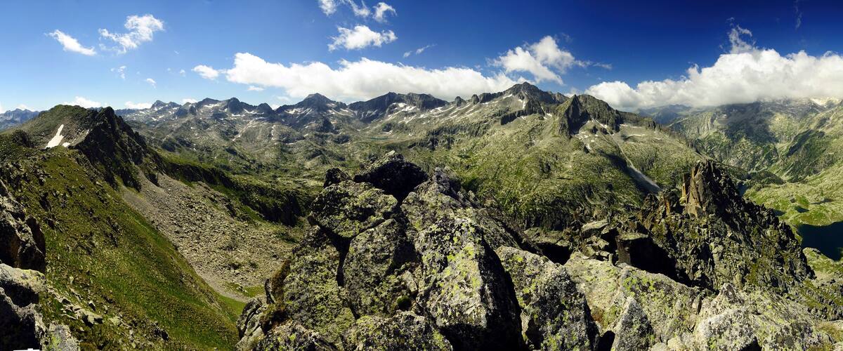 Rugged mountain terrain with rocky peaks and a valley with a lake.