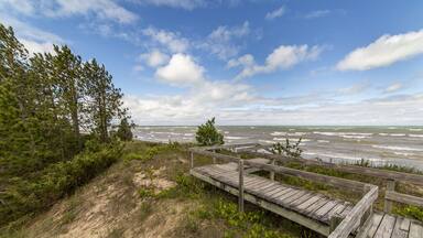 A wooden boardwalk leading to a beach with waves crashing onto the shore.