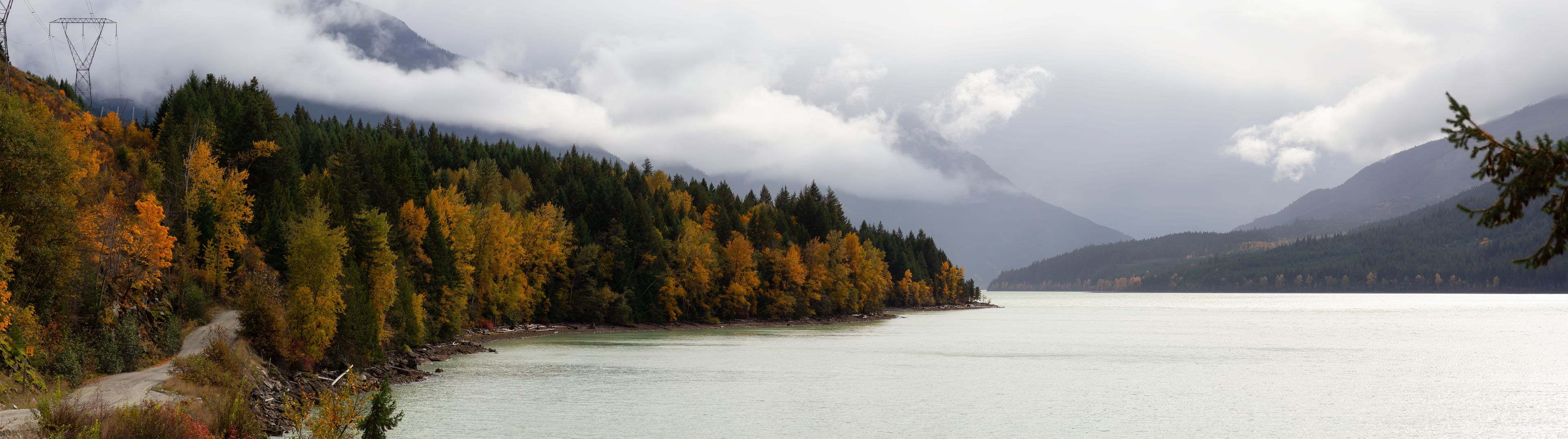Un lac entouré d’arbres aux couleurs automnales et de montagnes.