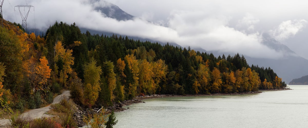 Un lac entouré d’arbres aux couleurs automnales et de montagnes.