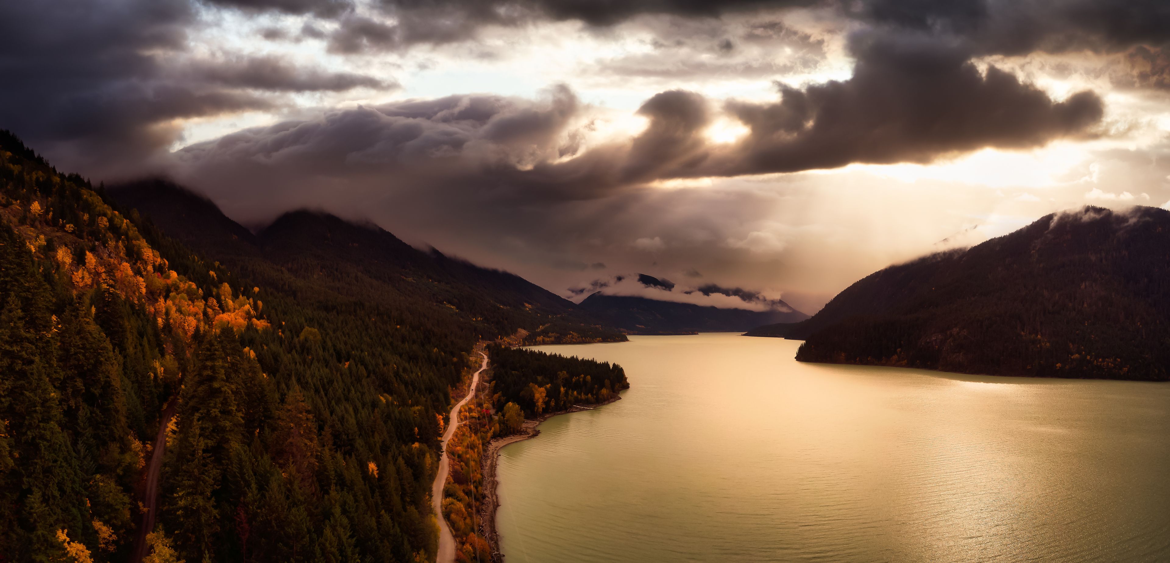 A lake surrounded by mountains with a road along the shore.