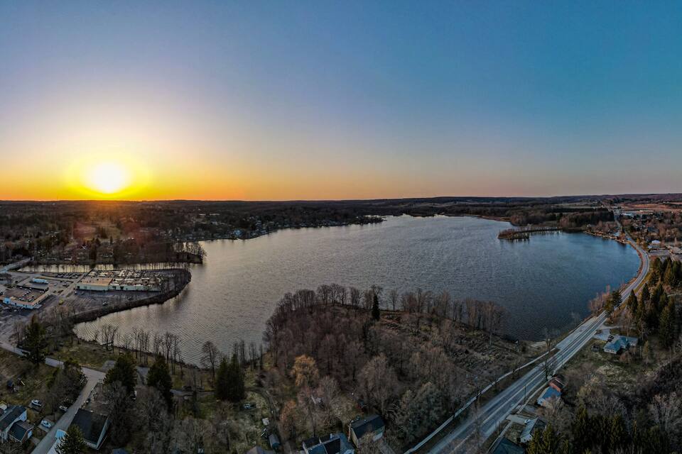 A sunset over a lake surrounded by residential areas and a bridge.