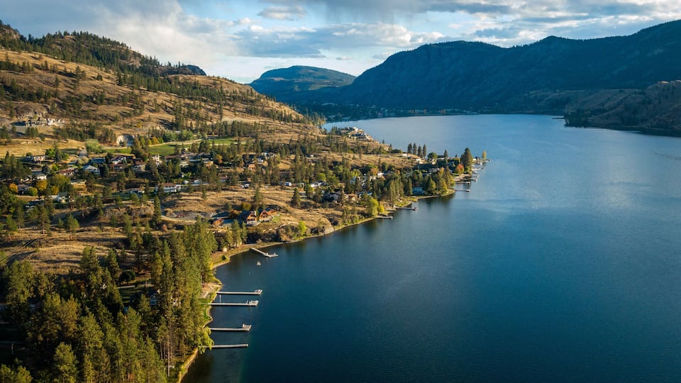 A lake surrounded by hills and a small town with houses and docks.