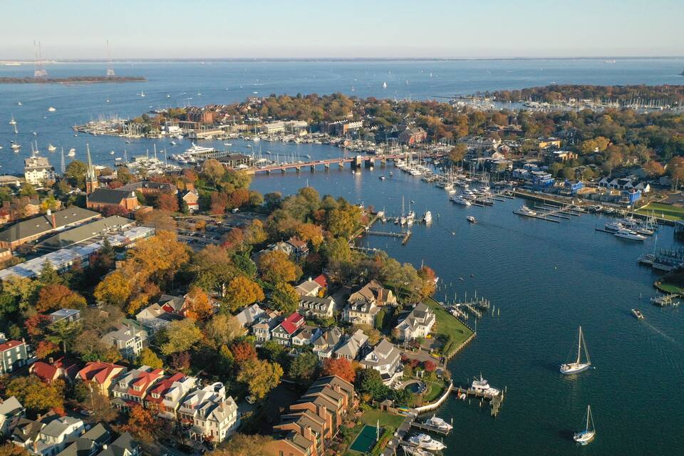 A coastal town with a marina, houses, and a bridge in the distance.