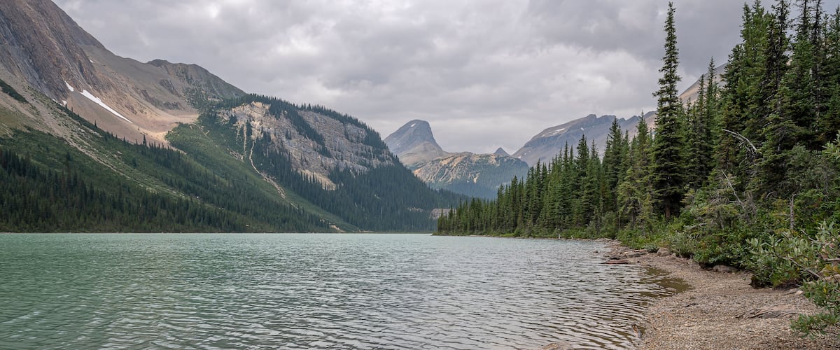 A calm lake surrounded by mountains and dense forests.