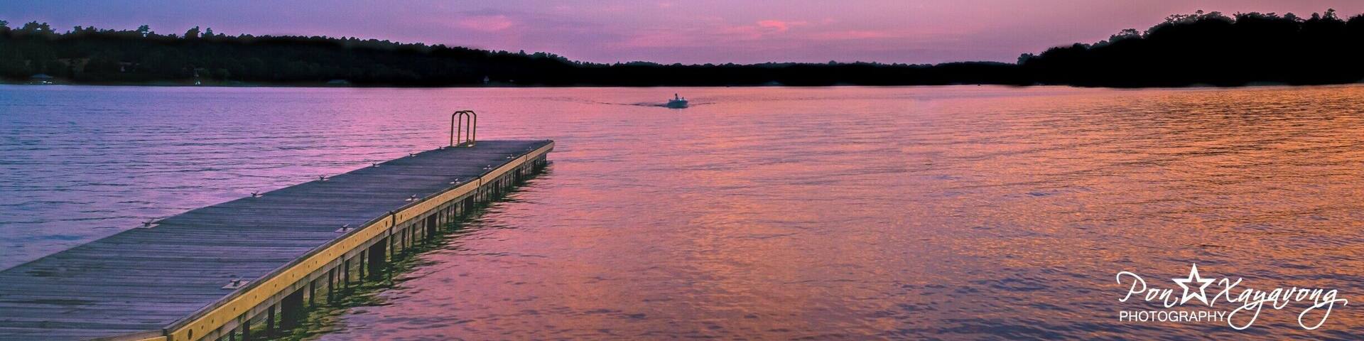 A sunset over a calm lake with a pier extending into the water.