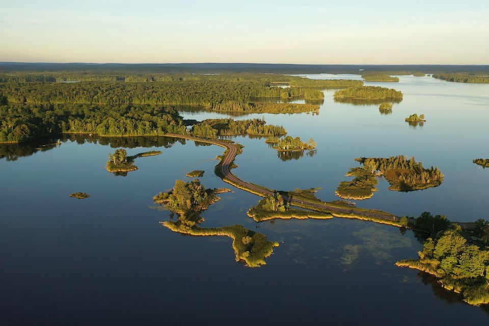 An aerial view of a river winding through a forested landscape with numerous small islands.