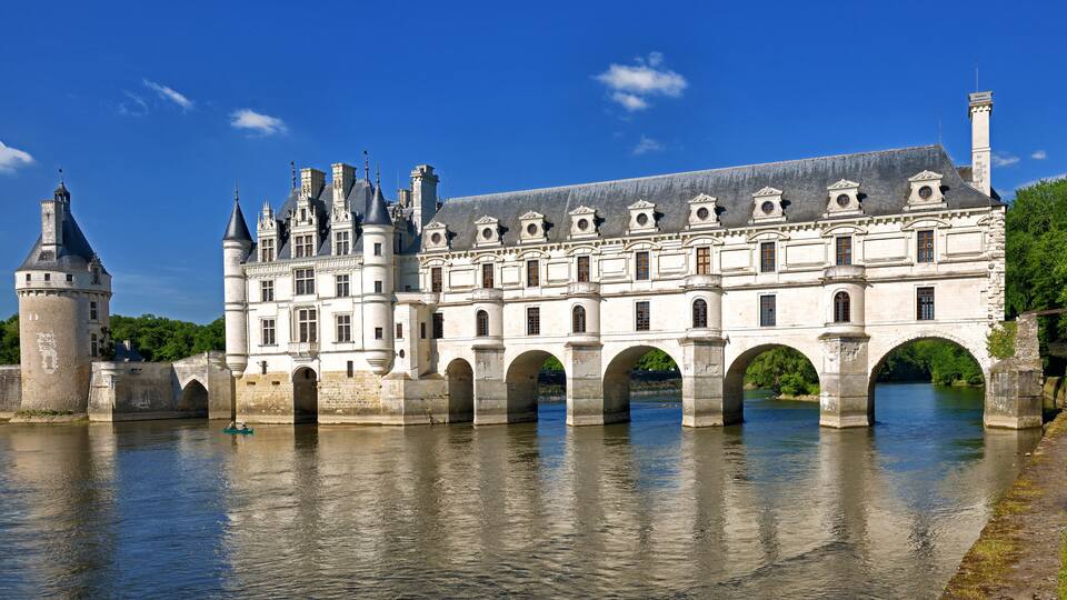 A historic building with a large arched bridge over a river.