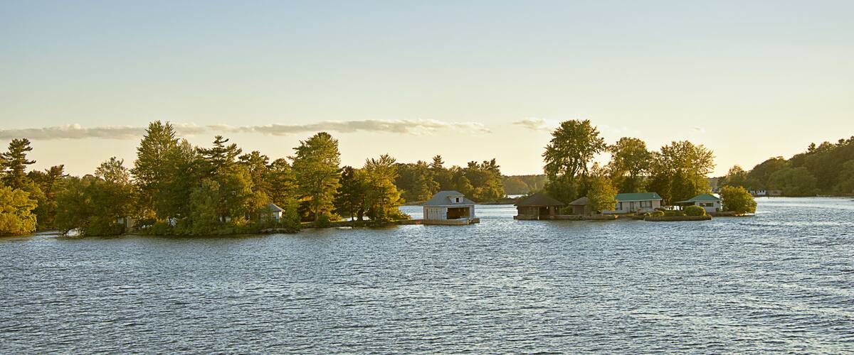 A calm lake with several small houses surrounded by trees.