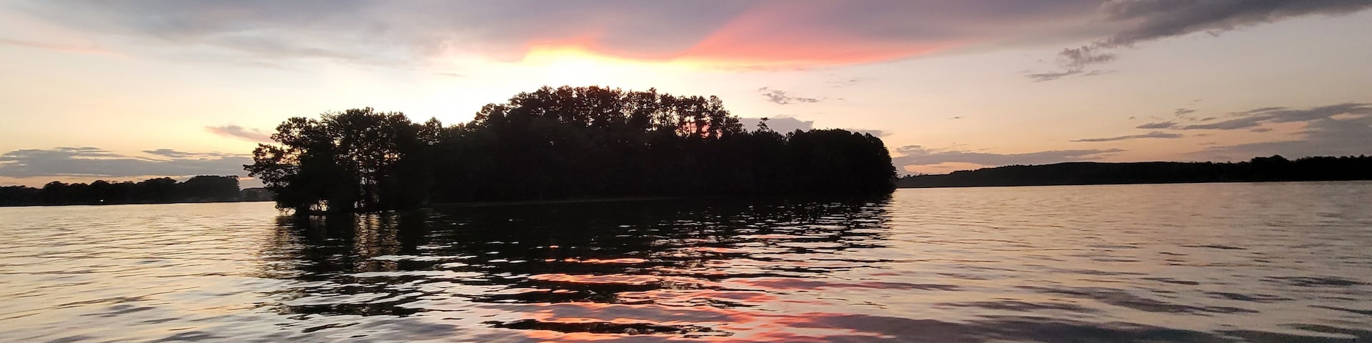 A sunset over a calm lake with an island silhouette.