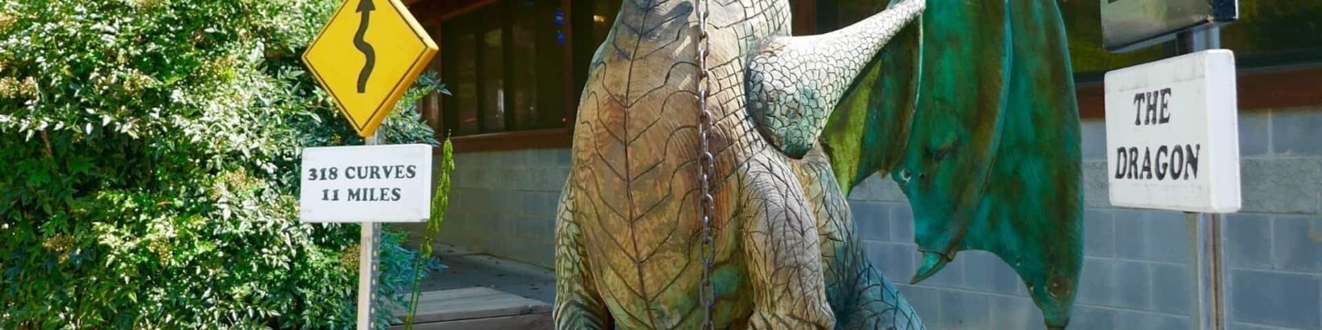 Una estatua de dragón con un letrero que dice "The Dragon" y una señal que indica 318 curvas en 11 millas.