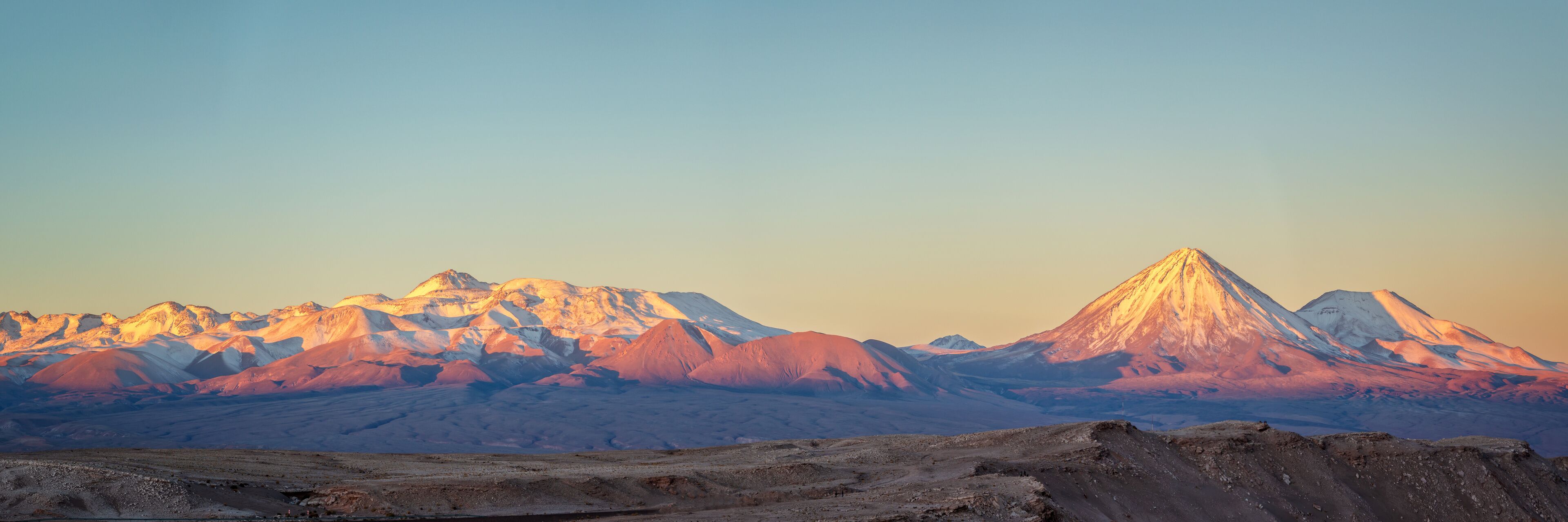 A mountain range with a prominent peak during sunset.