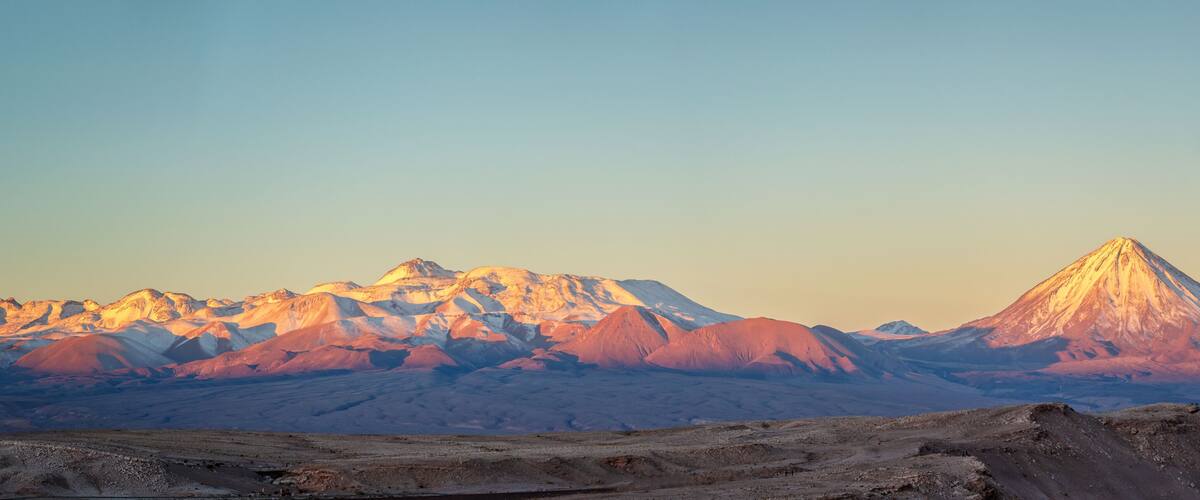A mountain range with a prominent peak during sunset.