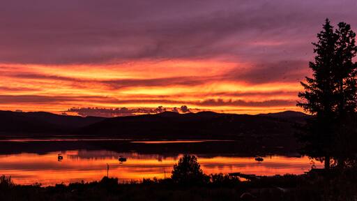 A sunset over a lake with mountains in the background.
