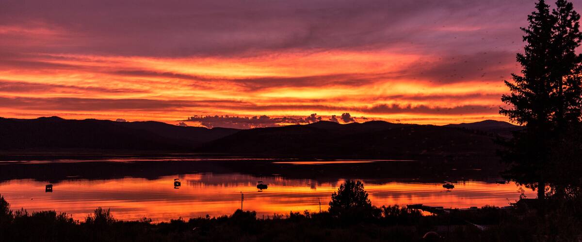 A sunset over a lake with mountains in the background.