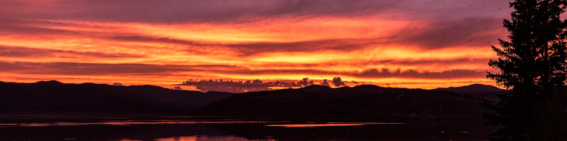 A sunset over a lake with mountains in the background.