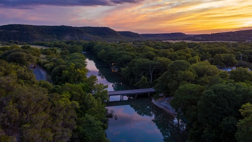 A river winding through a forested valley with hills in the background and a bridge crossing the river.