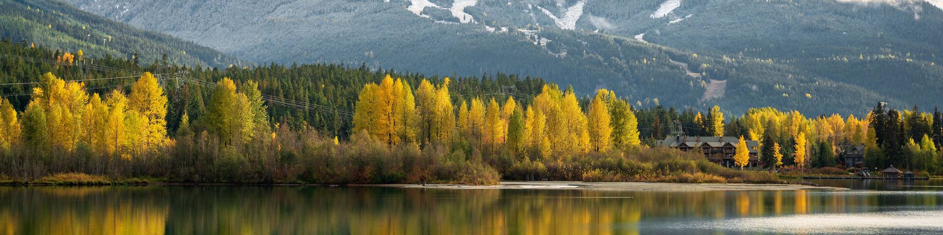 Green Lake in autumn with fall colours and a snow covered Whistler Mountain. Whistler BC, Canada.