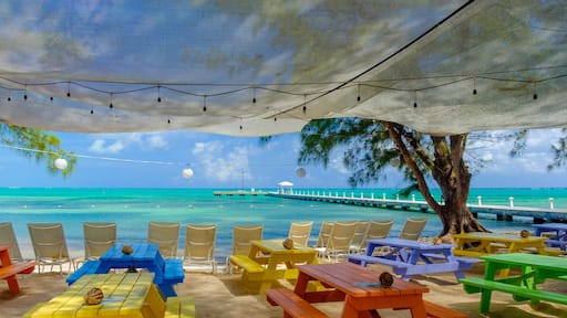 View of the Caribbean sea and Rum Point jetty from the beach with colorful tables , Grand Cayman, Cayman Islands
