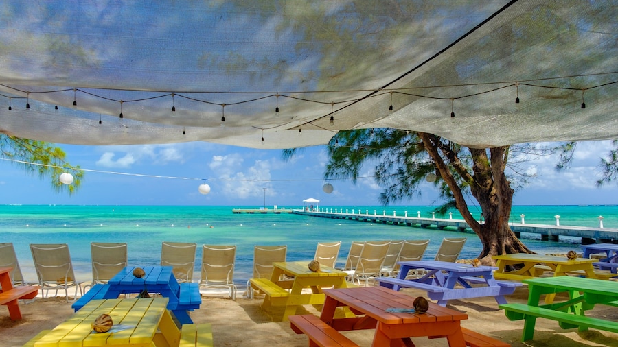 View of the Caribbean sea and Rum Point jetty from the beach with colorful tables , Grand Cayman, Cayman Islands