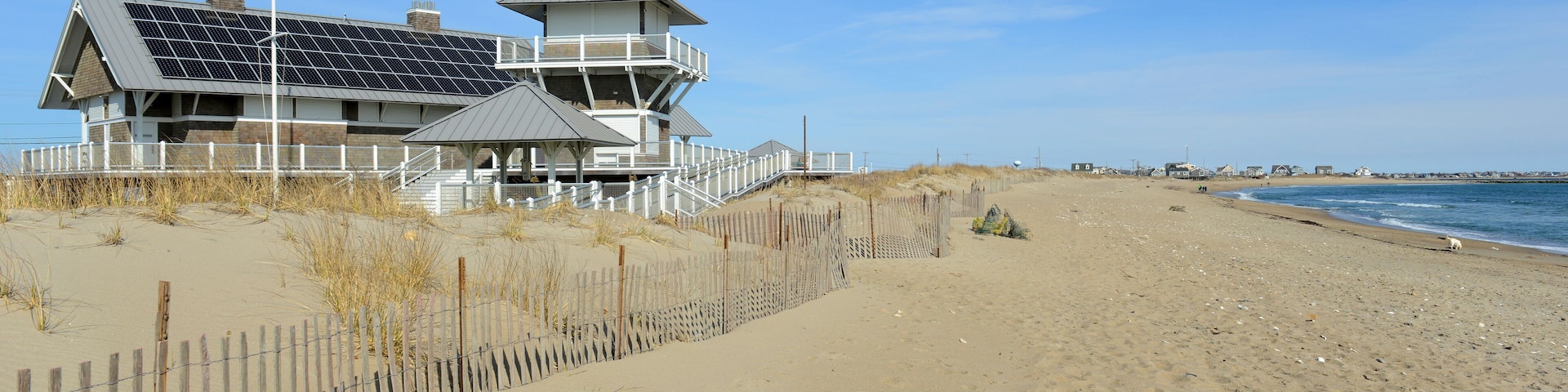 A beach house with solar panels, a wooden fence, and a clear blue sky.