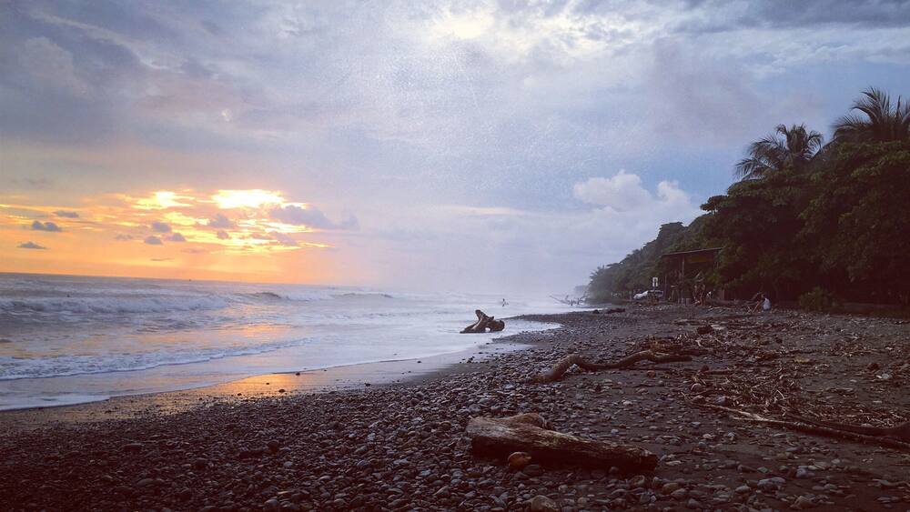 A rocky beach with a sunset in the background.