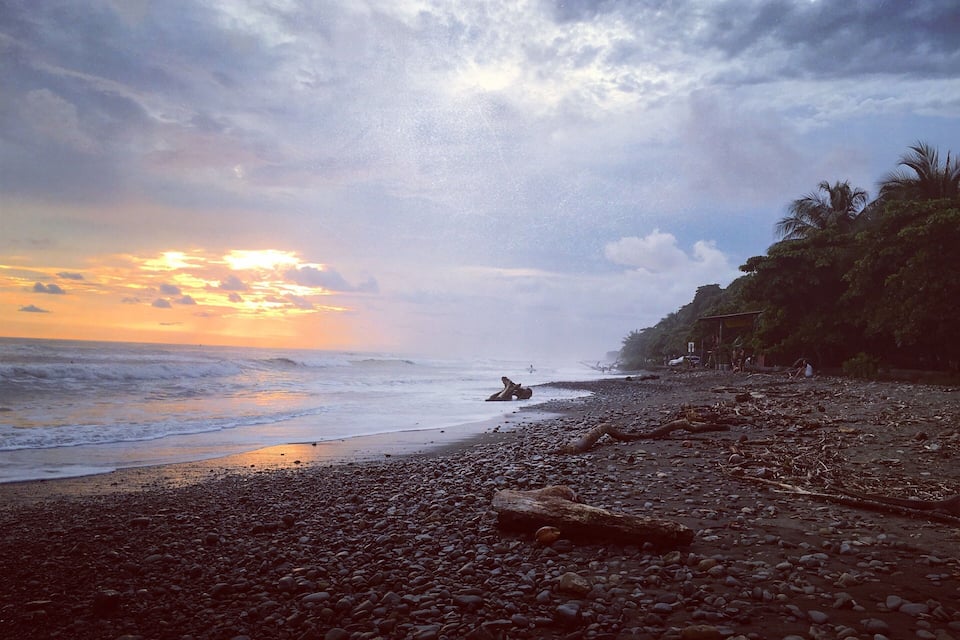 A rocky beach with a sunset in the background.