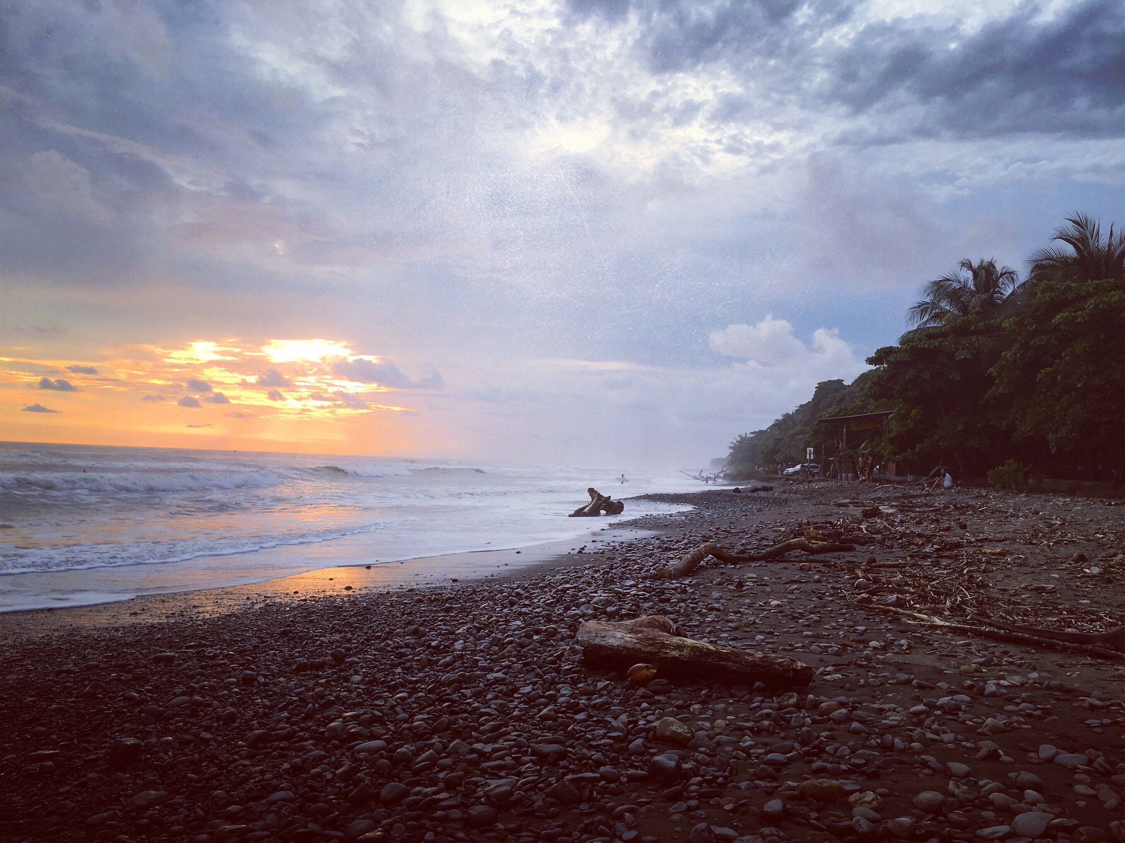 A rocky beach with a sunset in the background.