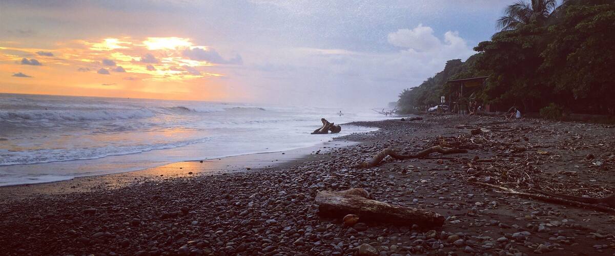 A rocky beach with a sunset in the background.