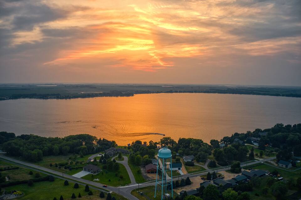 A sunset over a lake with a water tower and residential area.
