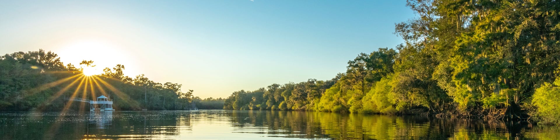 A calm river with trees reflecting the sunlight.