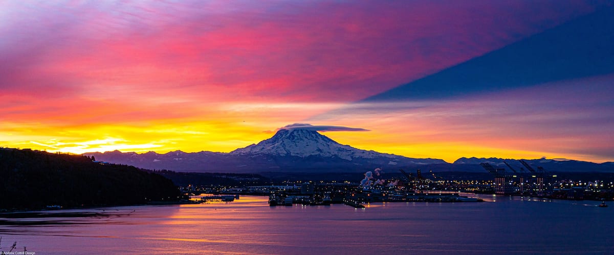 A mountain at sunset with a cityscape in the foreground.