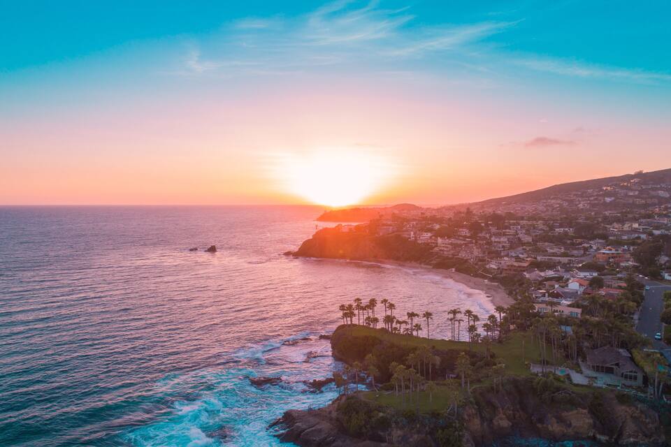 A coastal sunset with a beach, ocean, and residential area.