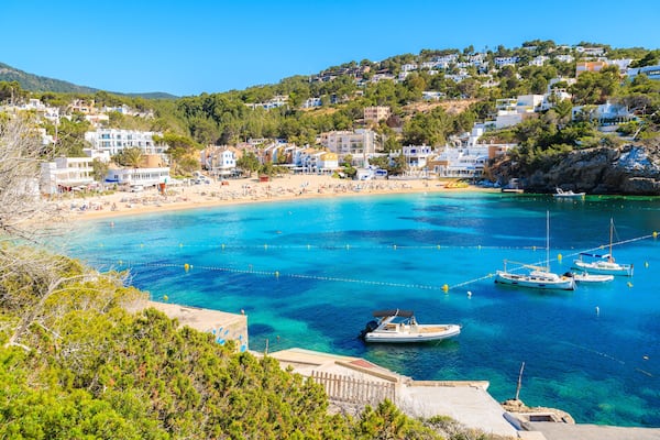 Fishing and sailing boats on blue sea water in Cala Vadella bay, Ibiza island, Spain