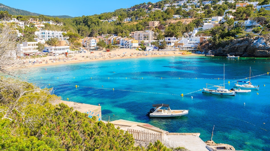 Fishing and sailing boats on blue sea water in Cala Vadella bay, Ibiza island, Spain