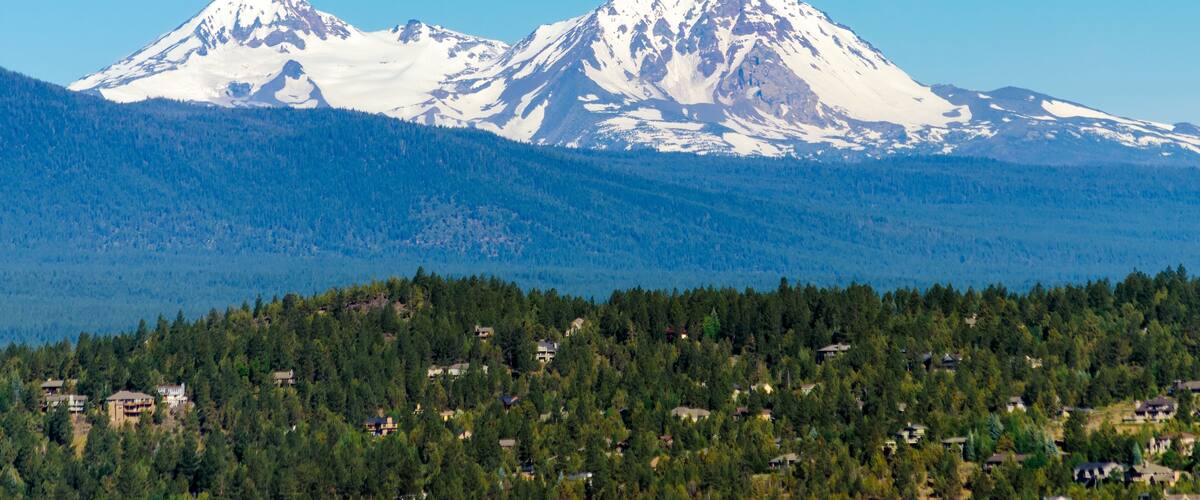 A snow-capped mountain range with a forested valley below.