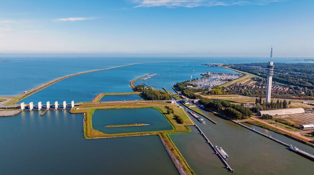 Luchtbeeld van een kuststad met een jachthaven, een vuurtoren en een brede waterweg.