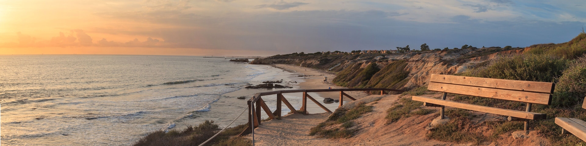 Bench along an outlook with a view at sunset of Crystal Cove Beach, Newport Beach and Laguna Beach line in Southern California
