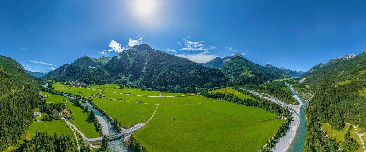 A valley with a river, green fields, and mountains.