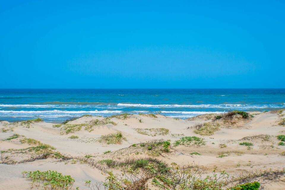 A sandy beach with gentle waves and clear blue sky.