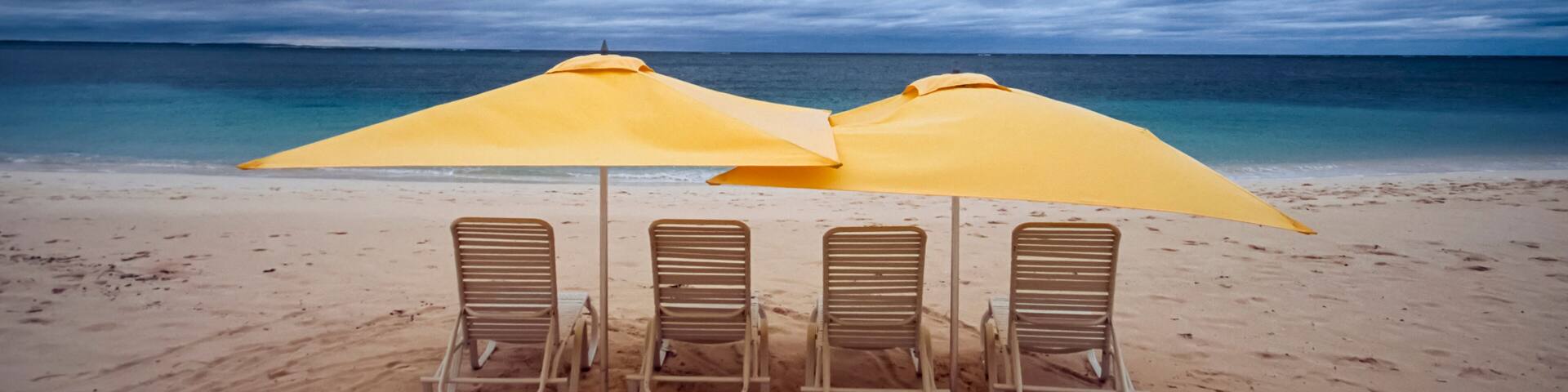 Lounge chairs and umbrellas on the beach on a cloudy day; Turks and Caicos Islands, West Indies