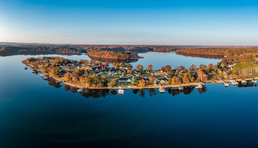 An aerial view of a lakeside community with houses, docks, and autumn foliage.