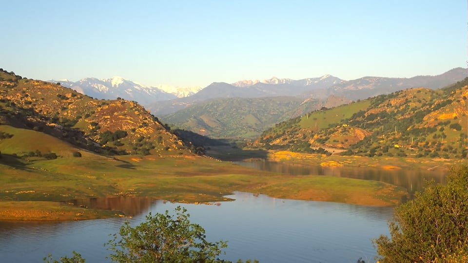 A valley with a lake surrounded by hills and mountains.